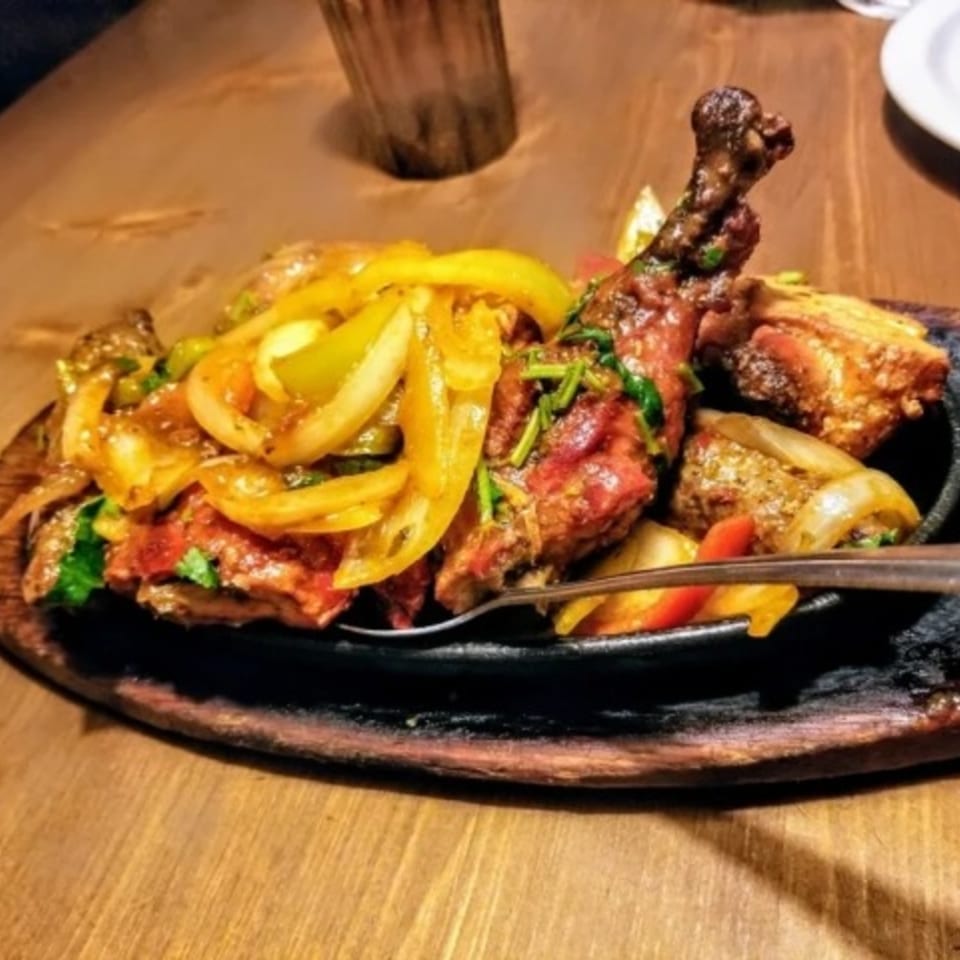 Sizzling Indian chicken dish with onions and peppers on a hot plate at Bombay South.
